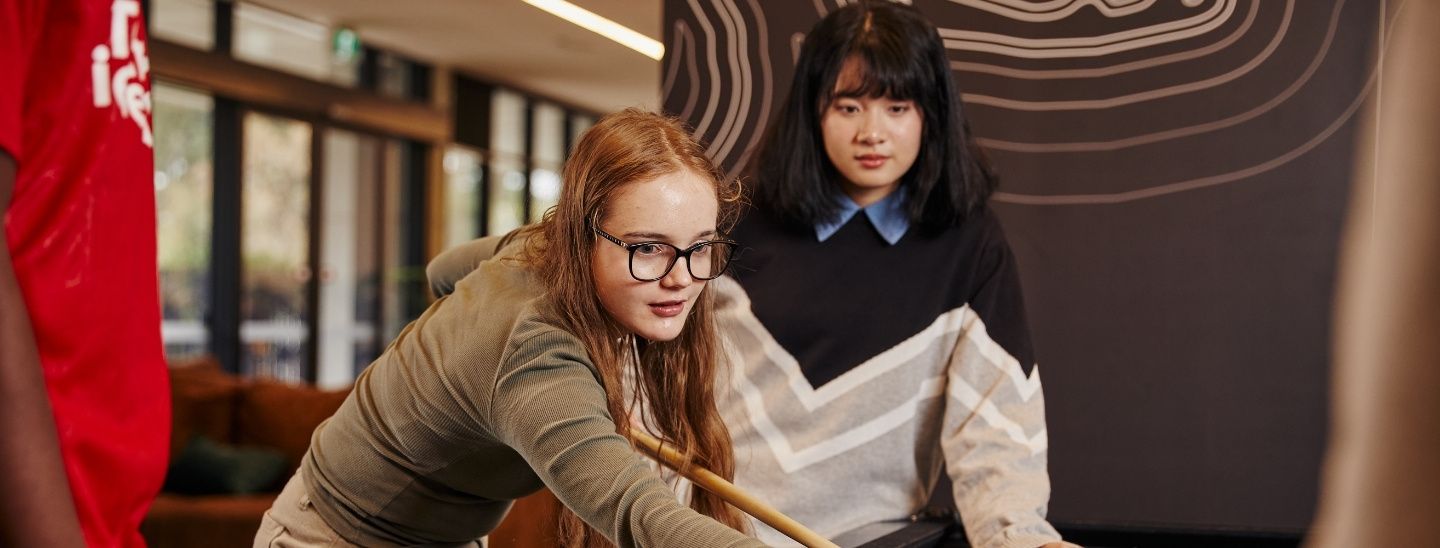 Female student playing 8-ball pool