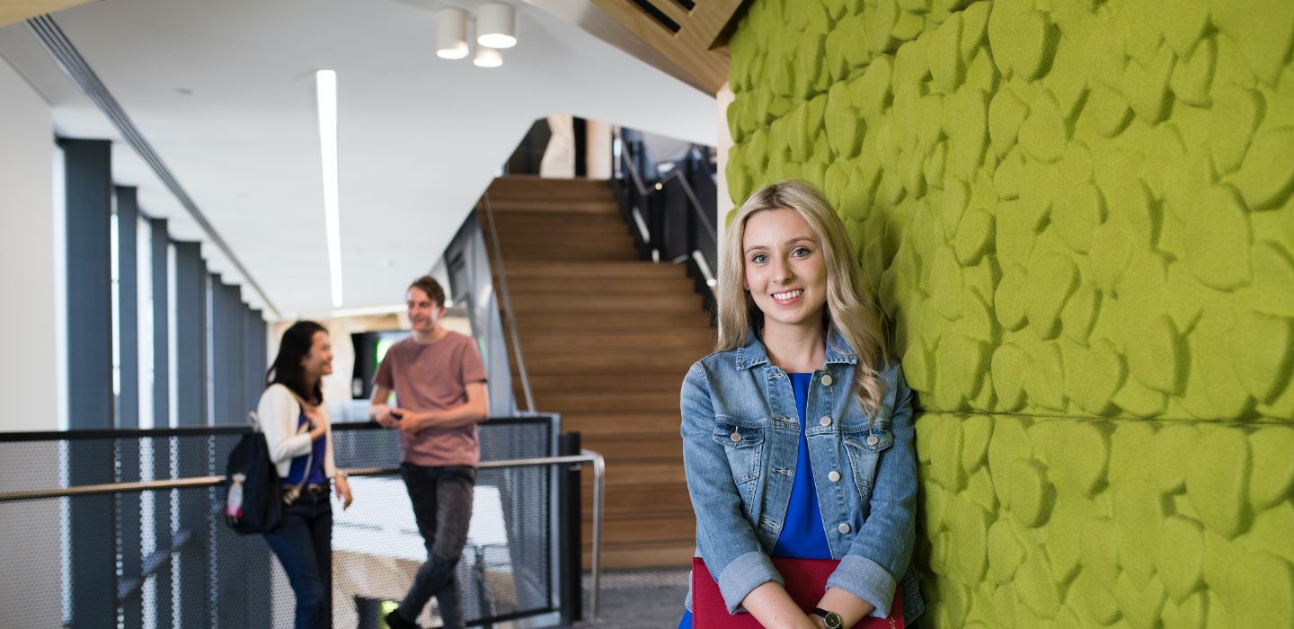 Campus female leaning on green wall