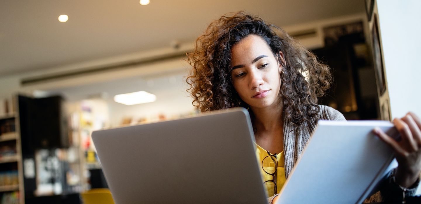 Campus female on laptop reading book