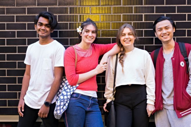 Campus group standing front of brick wall