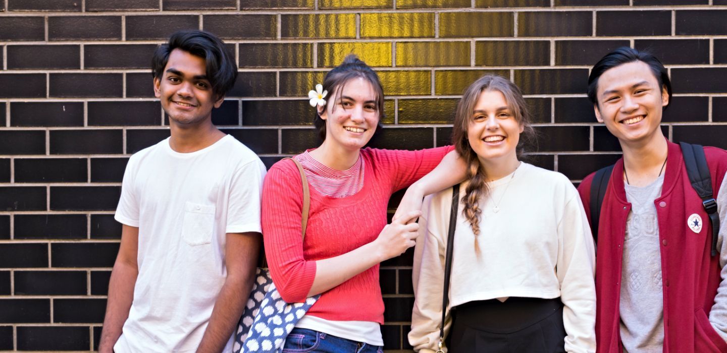 Campus group standing front of brick wall