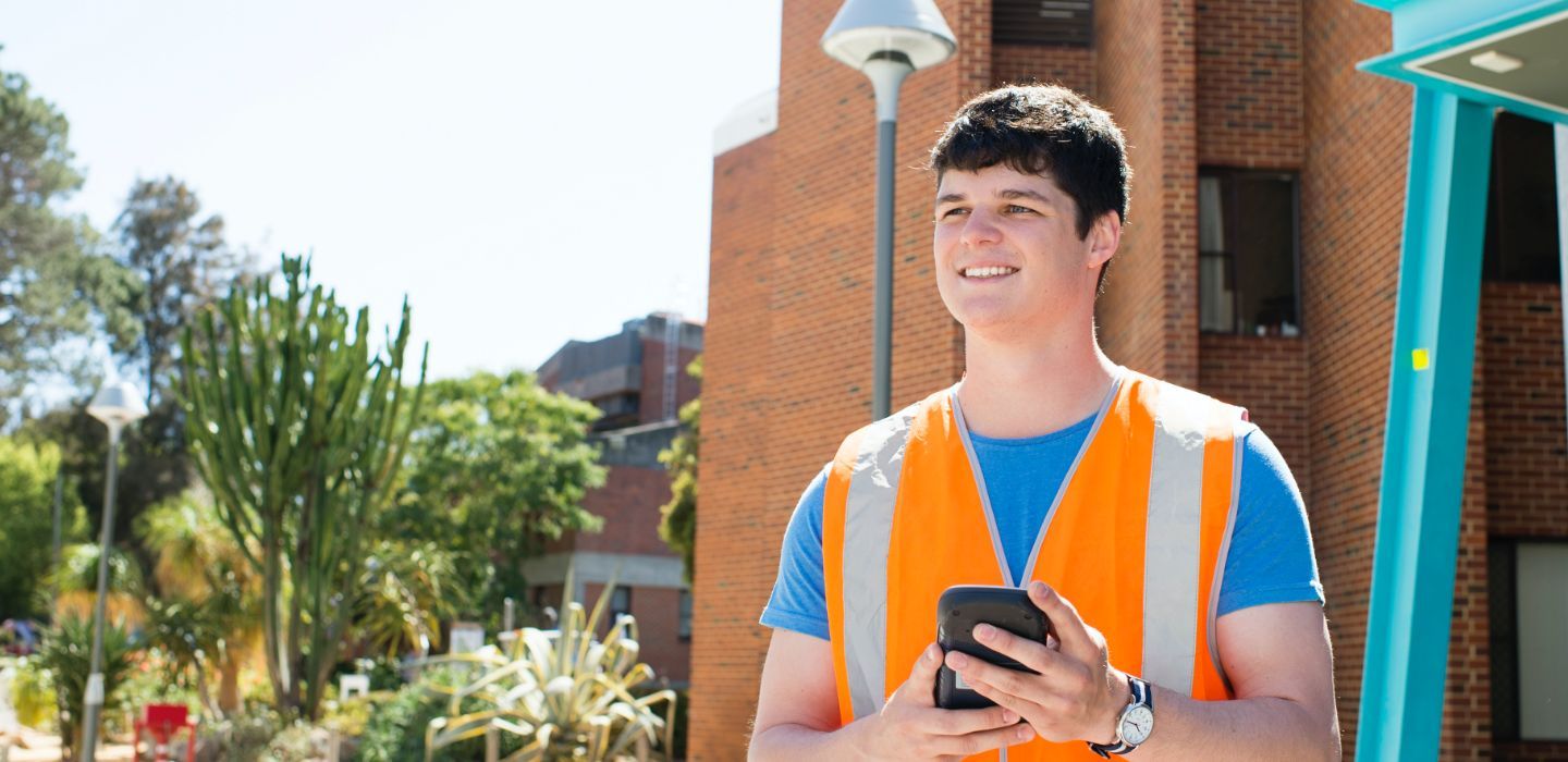 Campus male in vest standing outdoors