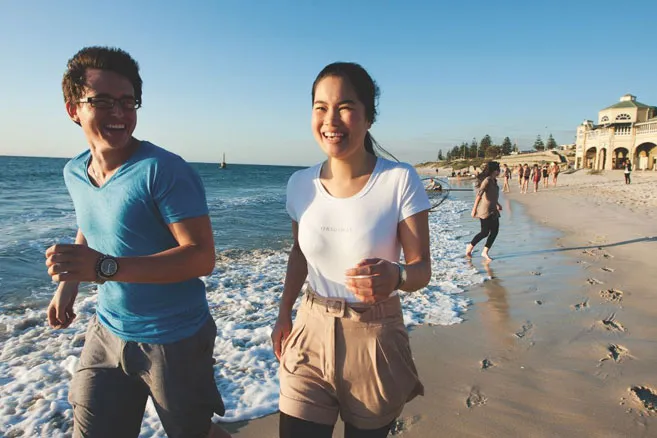 Off campus female and male walking on beach