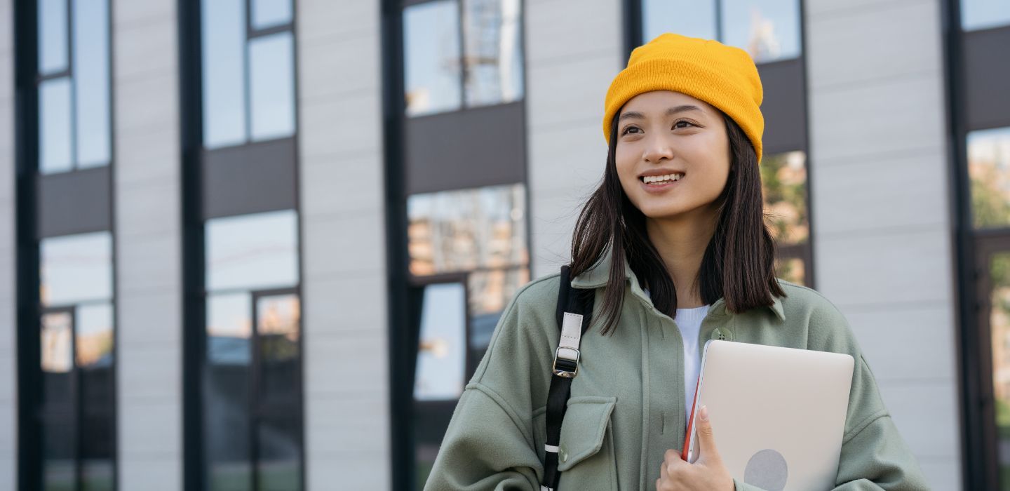 Off campus female holding laptop and bag
