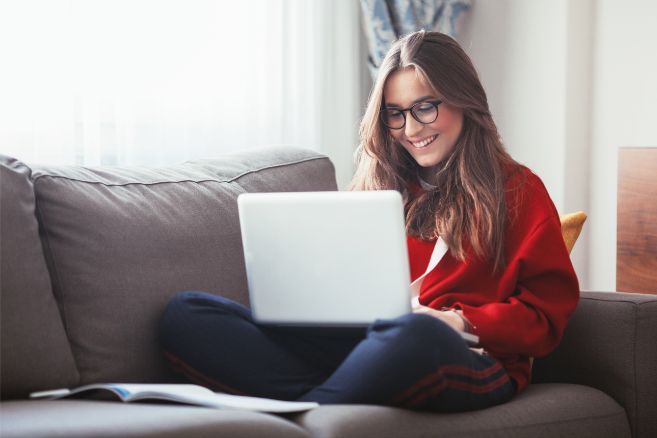 Off campus female looking at laptop sitting on couch