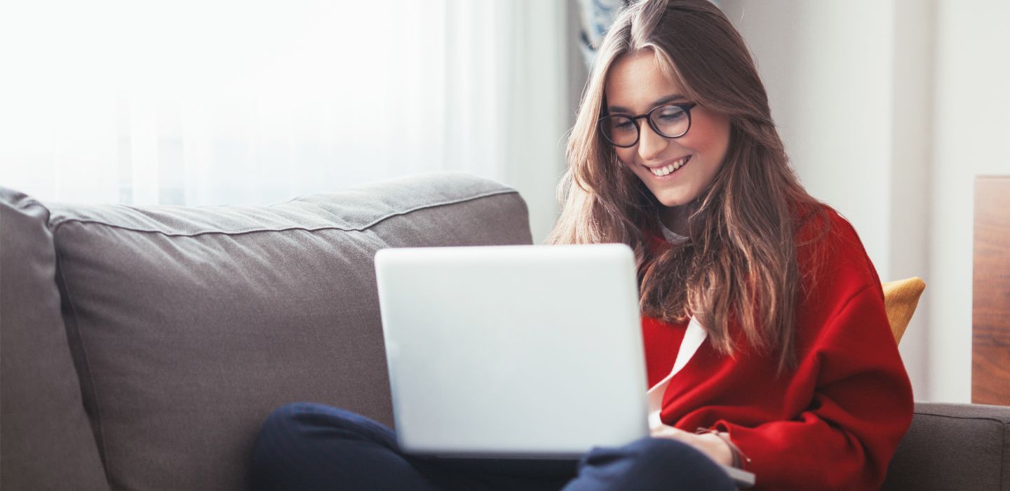 Off campus female looking at laptop sitting on couch