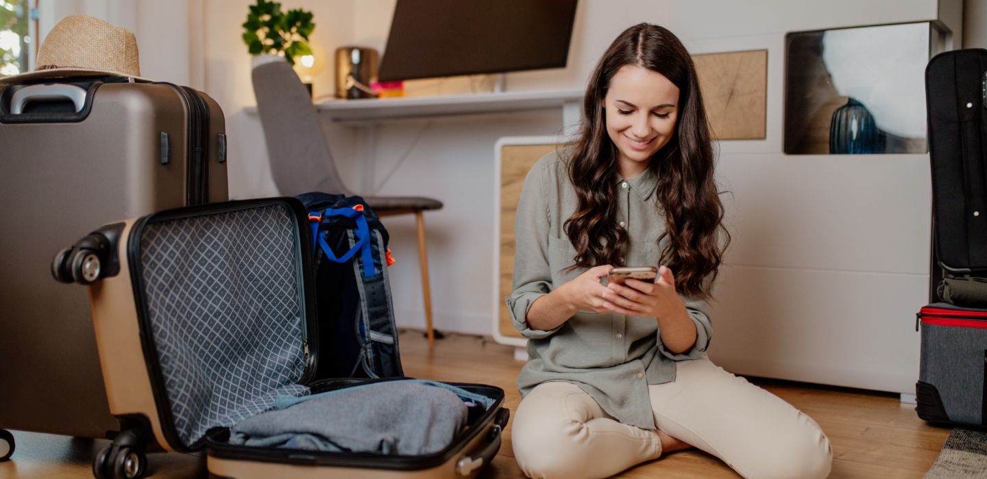 Off campus female on phone packing suitcase