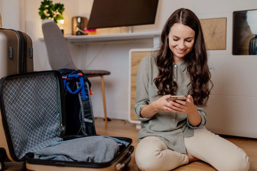 Off campus female on phone packing suitcase