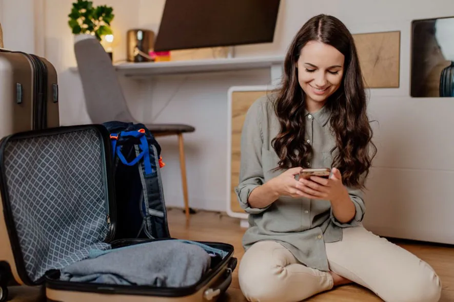 Off campus female on phone packing suitcase