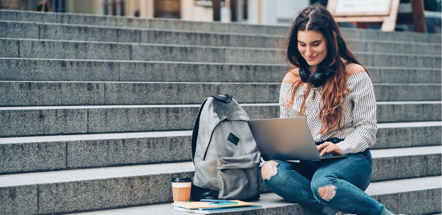 Off campus female sitting on stairs using laptop