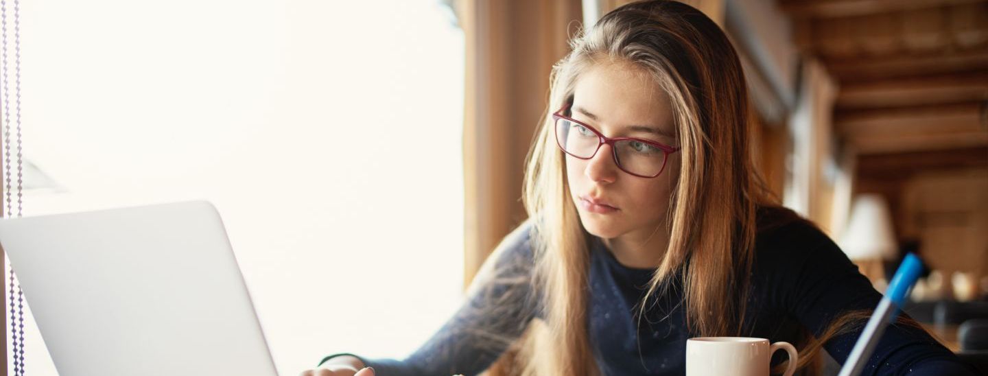Off campus female using laptop and writing in café