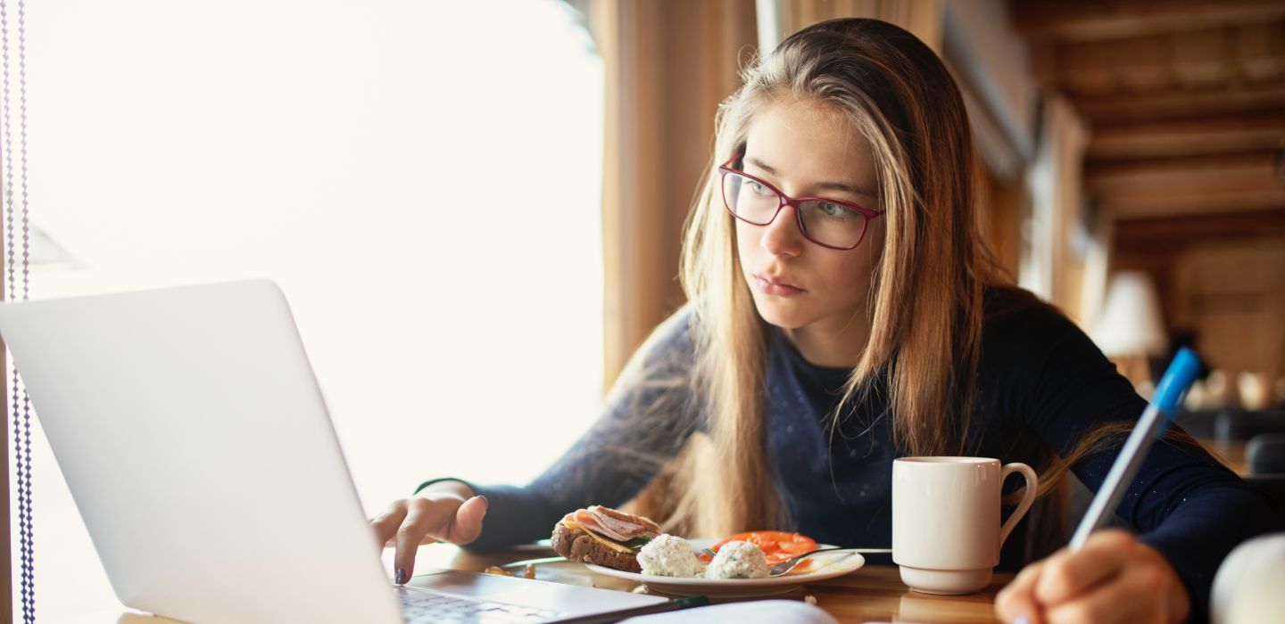 Off campus female using laptop and writing in café