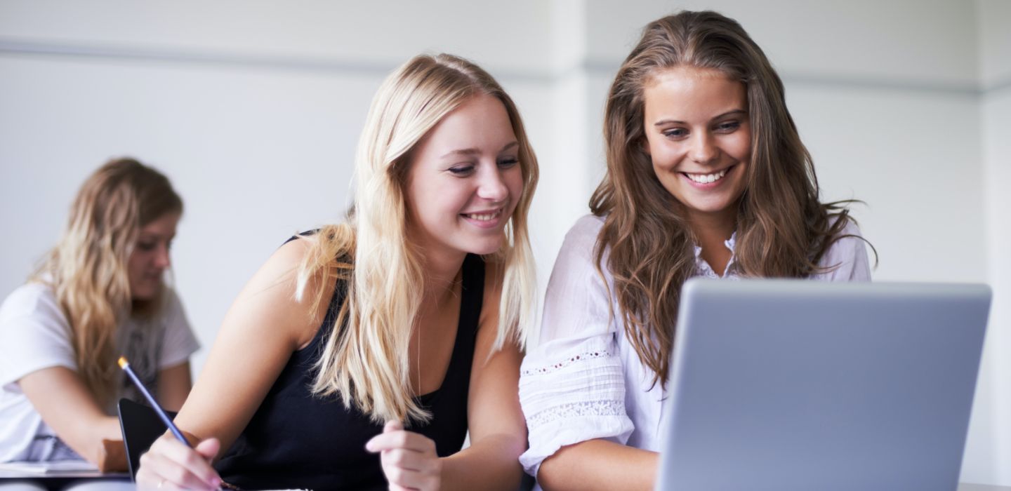 Off campus two females looking at laptop