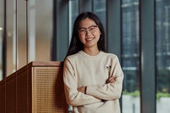 Female student standing before a glass window